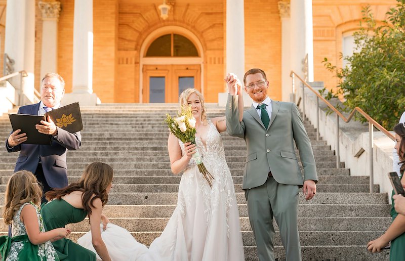 Newlywed couple celebrating outside their wedding venue.