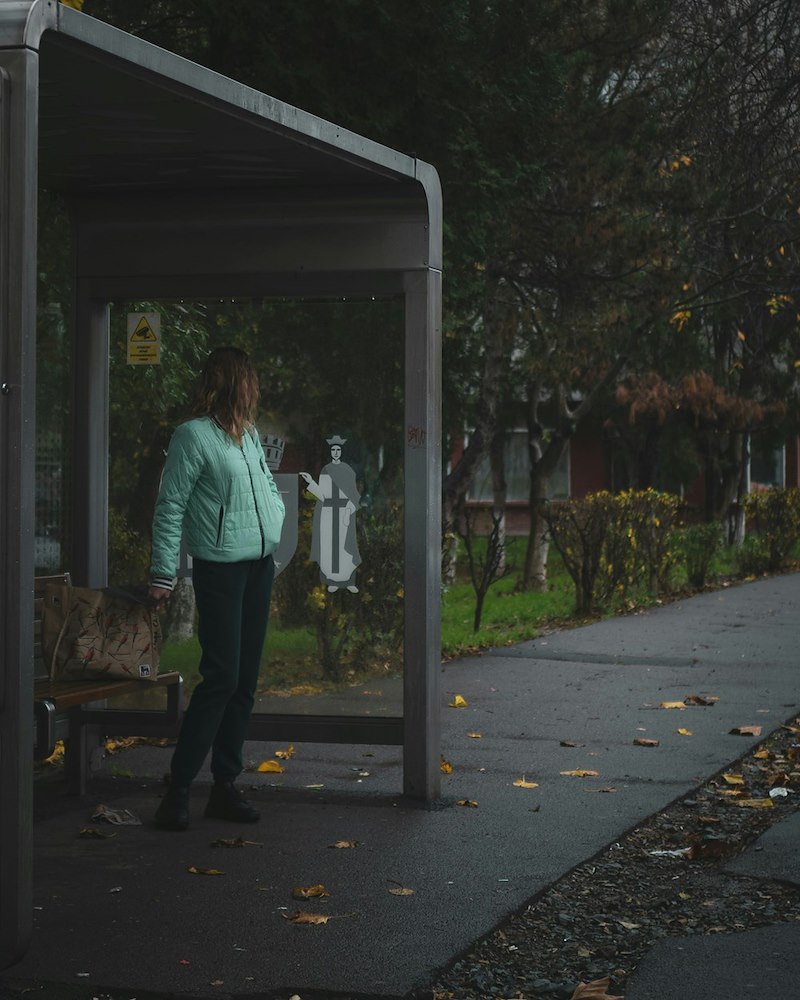 Woman waiting at a bus stop on a gloomy day