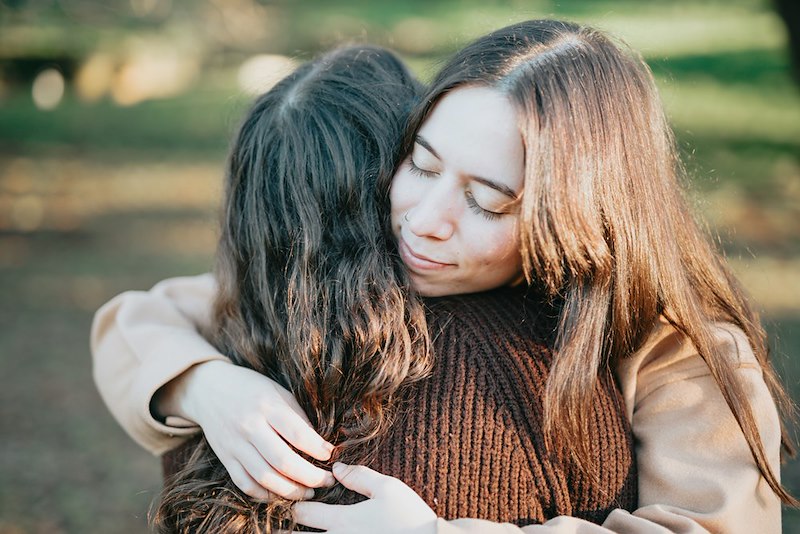 A woman hugs another woman, her friend