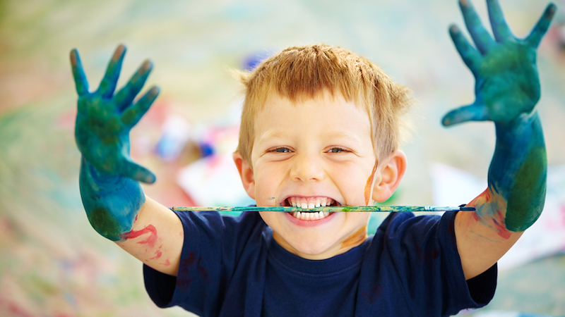 Messy kid with paint in his hands.