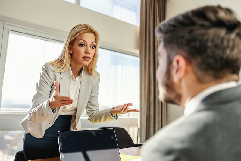 An angry boss gestures to her coworker below her
