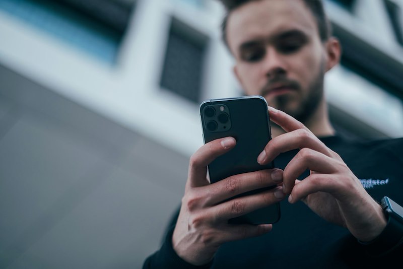 A man looks at his phone, enthralled by it.