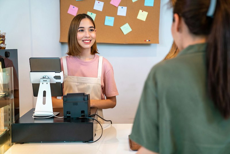 A woman behind a cafe counter serves a customer