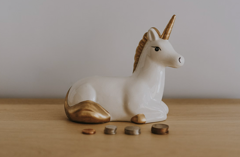 A unicorn piggy bank and coins, representing the "unicorn" candidate the recruiter claimed the advertised offer had been for