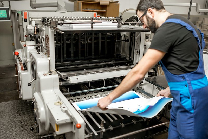 Printing company worker operating commercial printing equipment.