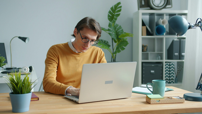 An employee works on his laptop at his desk.
