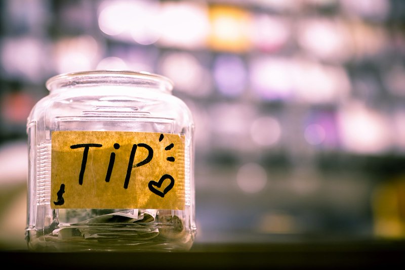 A tip jar on a counter at a coffee shop