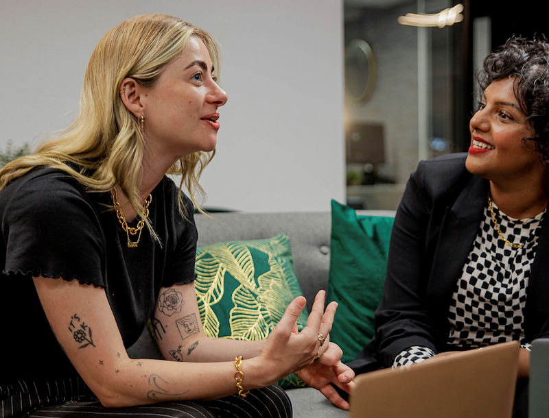 Two employees engage in small talk at the office