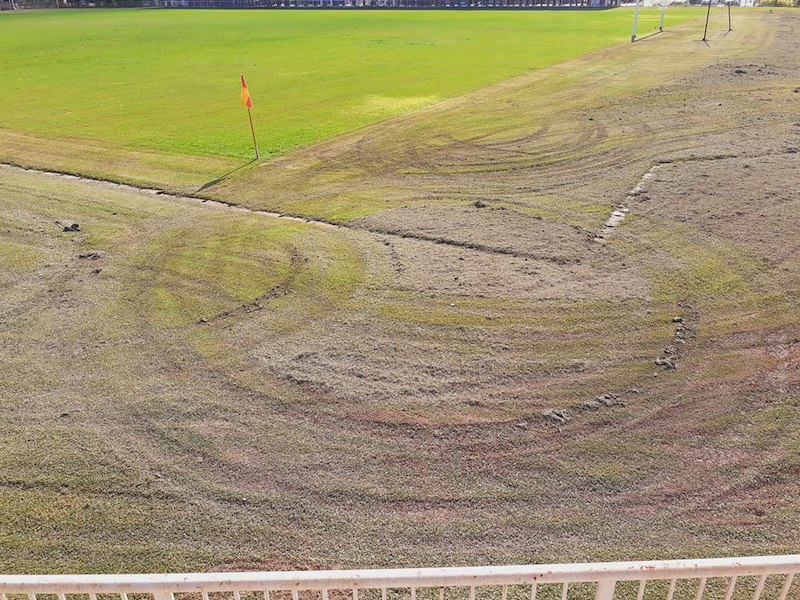 Damaged grass covered in deep tire tracks and worn patches across a large lawn