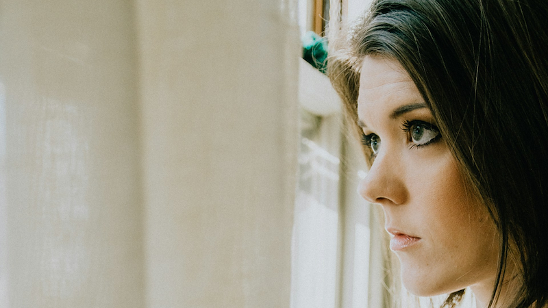 Close-up of a woman looking out of a window.