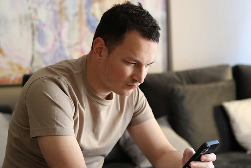 A stressed out man looks at his phone in his hand