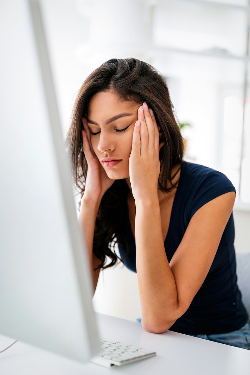 Frustrated homeowner sitting at her computer, hands on her head.