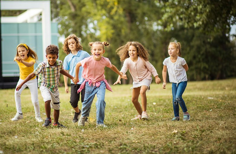A group of children running and playing together in the front yard of the home.
