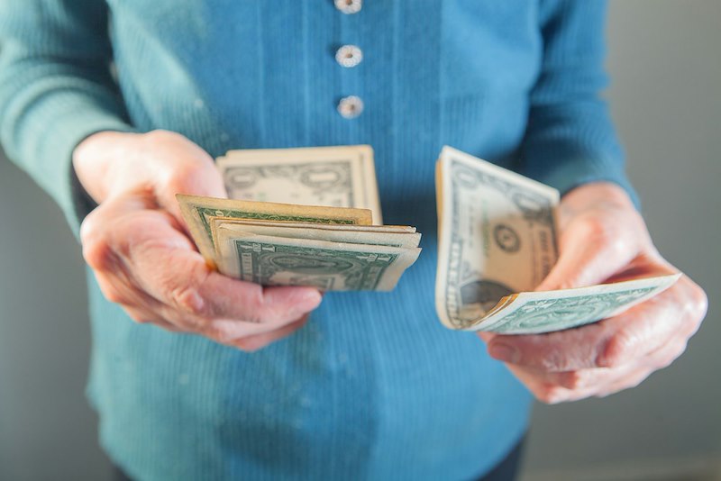 A person counts out one dollar bills in their hand