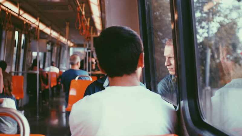 A teen in a white shirt rides the bus home