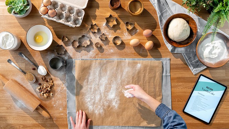 Overhead view of ingredients, cookie cutters, and a digital recipe on a tablet.