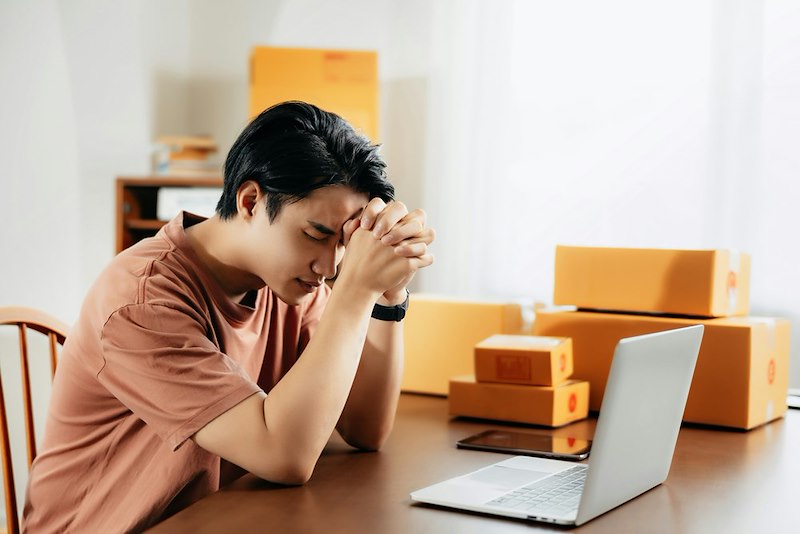 A frustrated man puts his hands to his head at his desk
