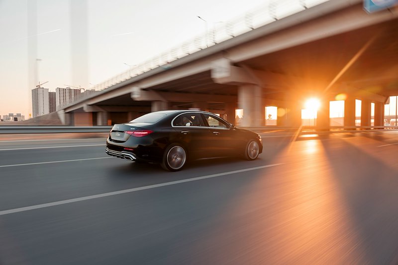 A fancy black car being driven on the road.
