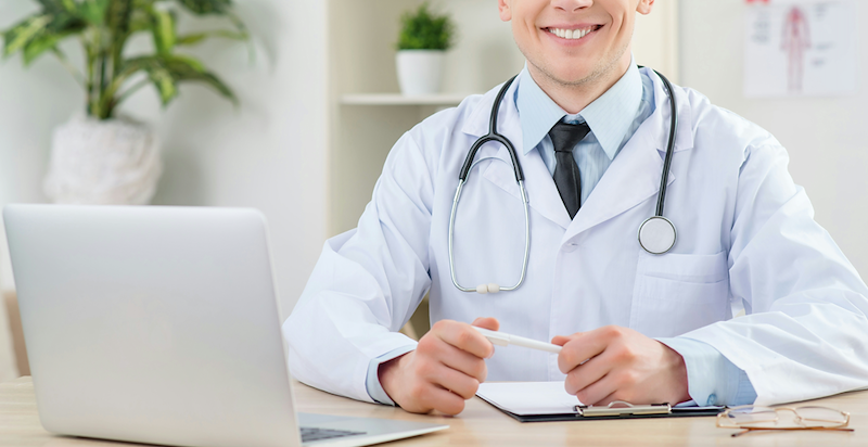 A doctor smiles at his desk