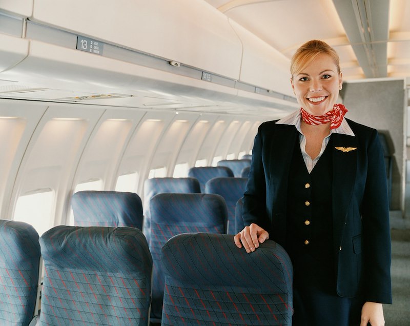 A flight attendant smiles in a plane.