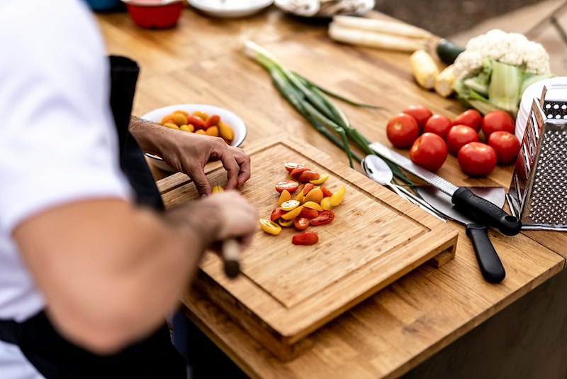 A man chops up tomatoes on a cutting board