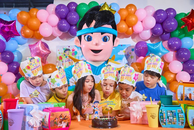 A kid's birthday party with balloons, decorations, and cake. Model portrayal.