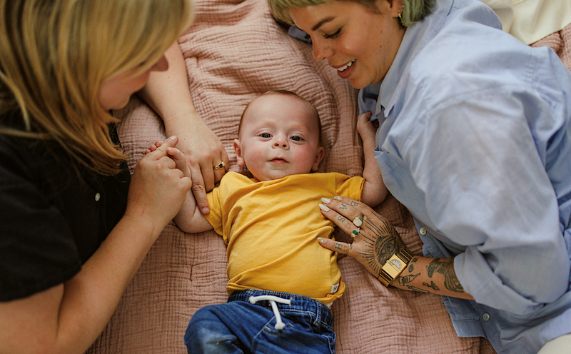Two friends look at a baby
