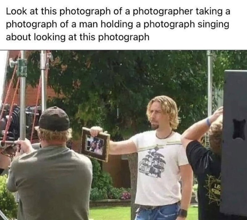 Look at this photograph of a photographer taking a photograph of a man holding a photograph singing about looking at this photograph LE Filte