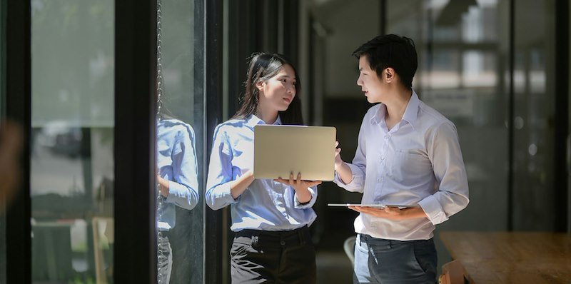 Two young professionals discuss something outside the workplace