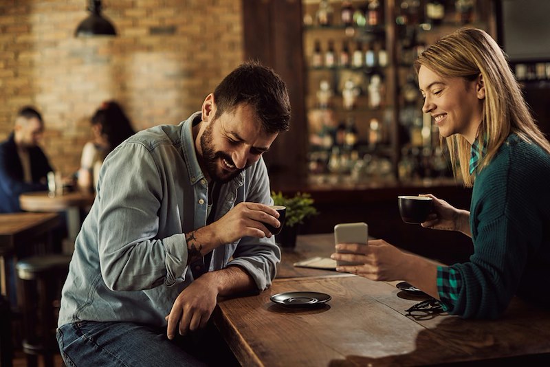 A woman shares something on her phone with her date at a table