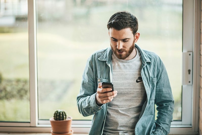 A man looks down at his phone, confused