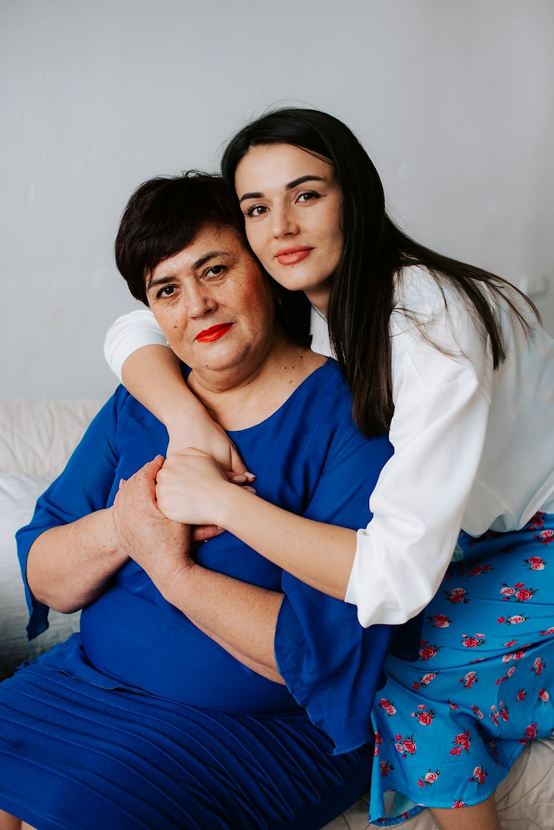 A mother and her adult daughter hugging.