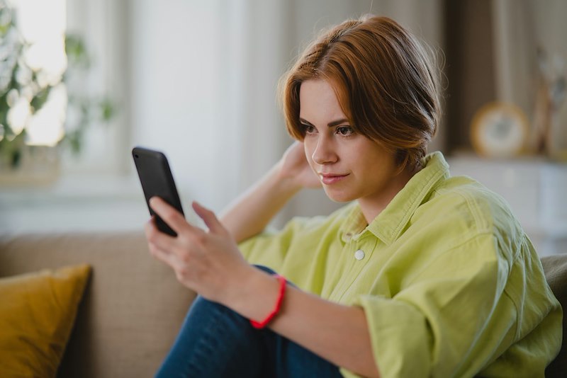 A woman looks at her phone contemplatively