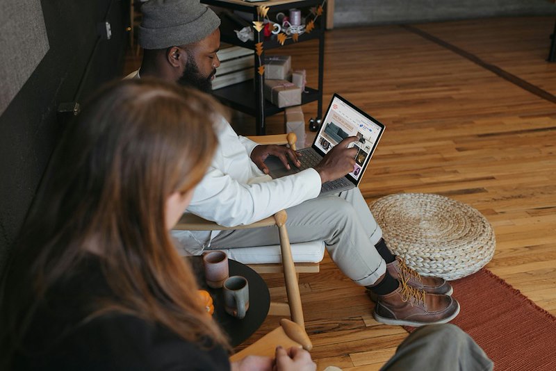 A woman looks at her coworker's screen over his shoulder