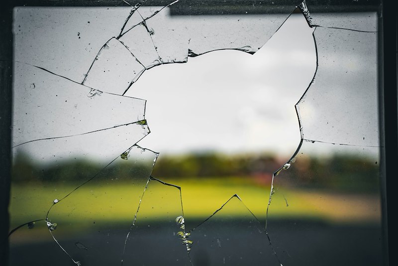 A window with broken glass from the neighbor's kid's ball