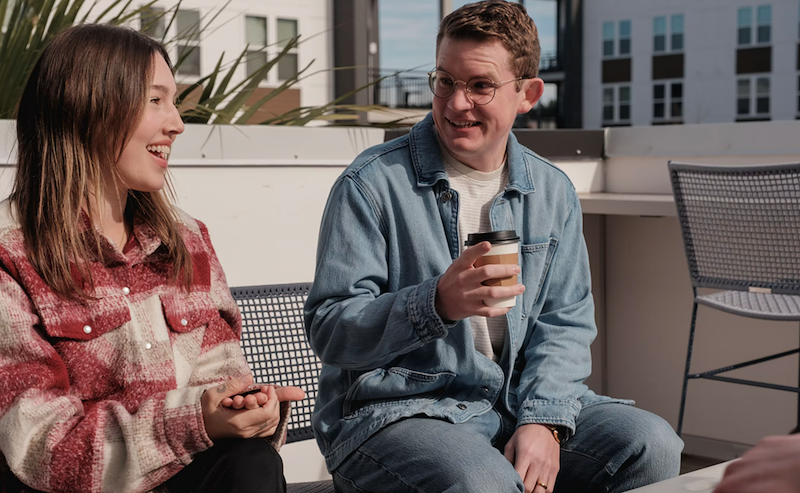 Neighbors having a conversation over coffee on the rooftop of an apartment
