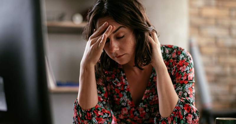 A stressed woman works at her desk after learning that her old boss expects her to stay at her job for an extra week, even though she'll be working at a new company when she's expected to work.