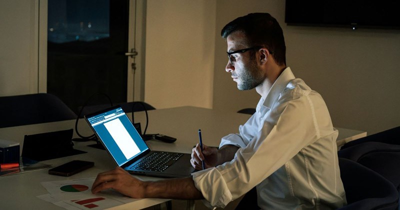 A man sitting at a table using a laptop computer
