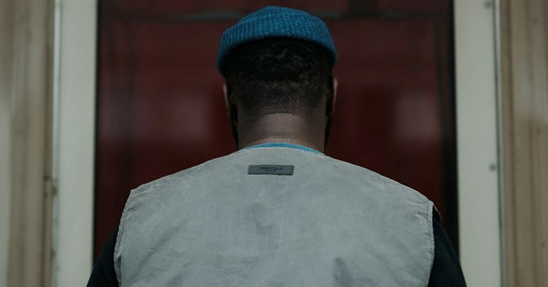 The back of a man's head as he stands in front of a front door