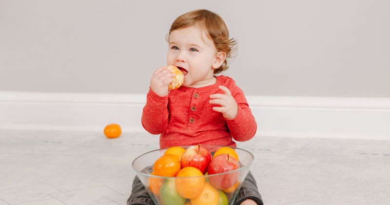 A baby eating a bowl of fruits