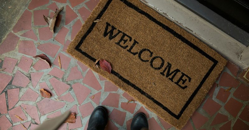 Boots next to a brown and beige welcome mat in front of a front door