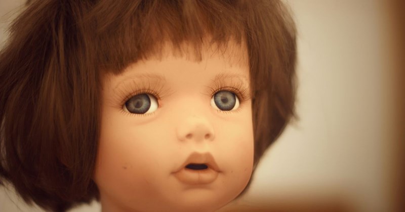A doll with blue eyes, brown hair, and a bad haircut