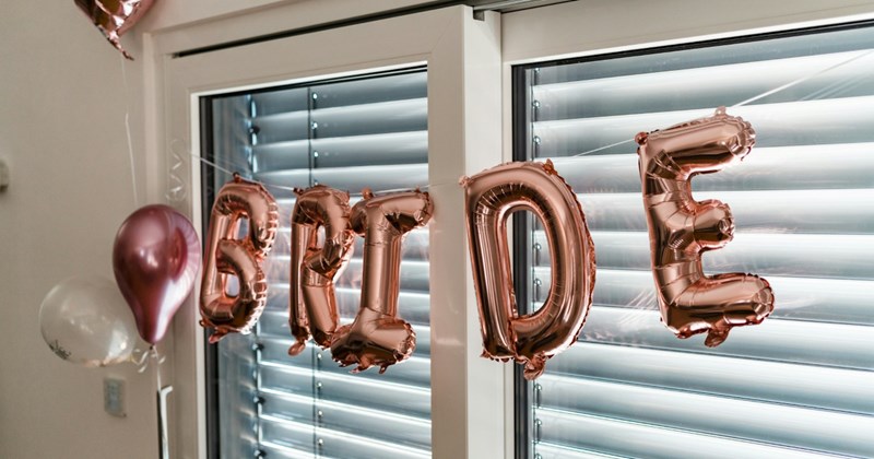 Pink letter balloons strung across a window, spelling 'bride'