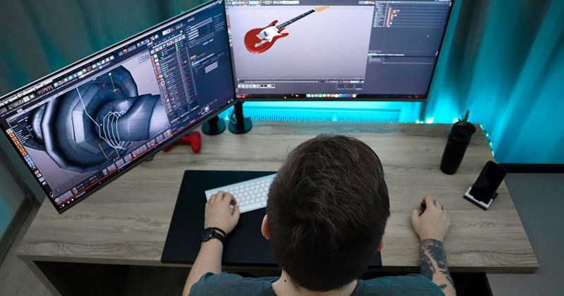 A male animator sits at a desk and works on an animation of a guitar 