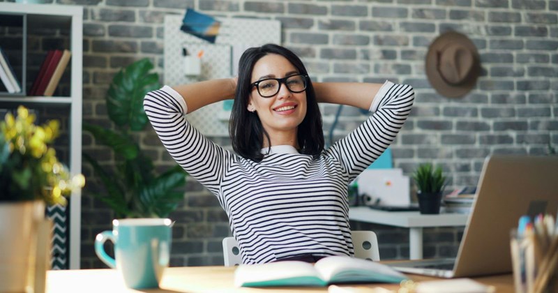A satisfied employee leans back at her desk and smiles