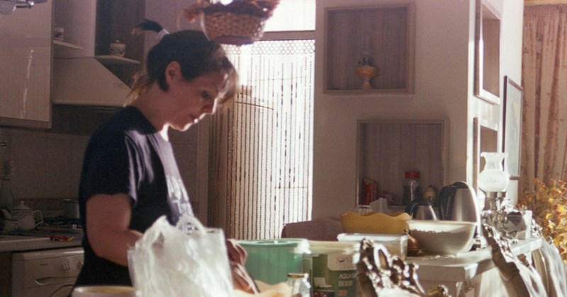 A woman prepares food in a small open-plan kitchen