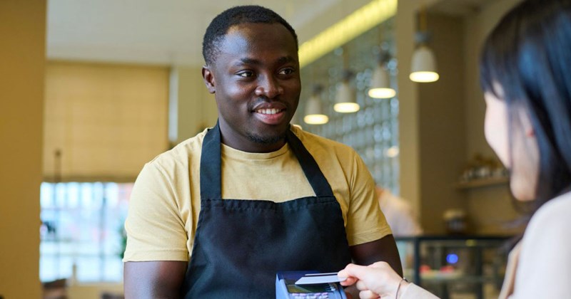 Young male employee presents card reader to a customer