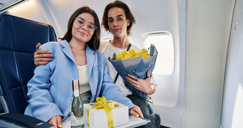 Cute tranquil young man and his smiling beautiful dark-haired girlfriend in eyeglasses sitting in the first class cabin