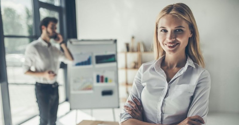 A professional woman dressed formally, standing proud and smiling