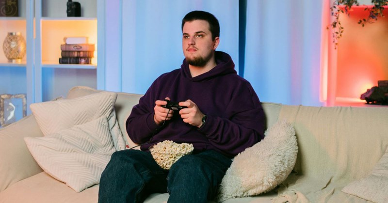 Boyfriend sits on the couch playing video games while his girlfriend works hard, making extra money to pay his rent.